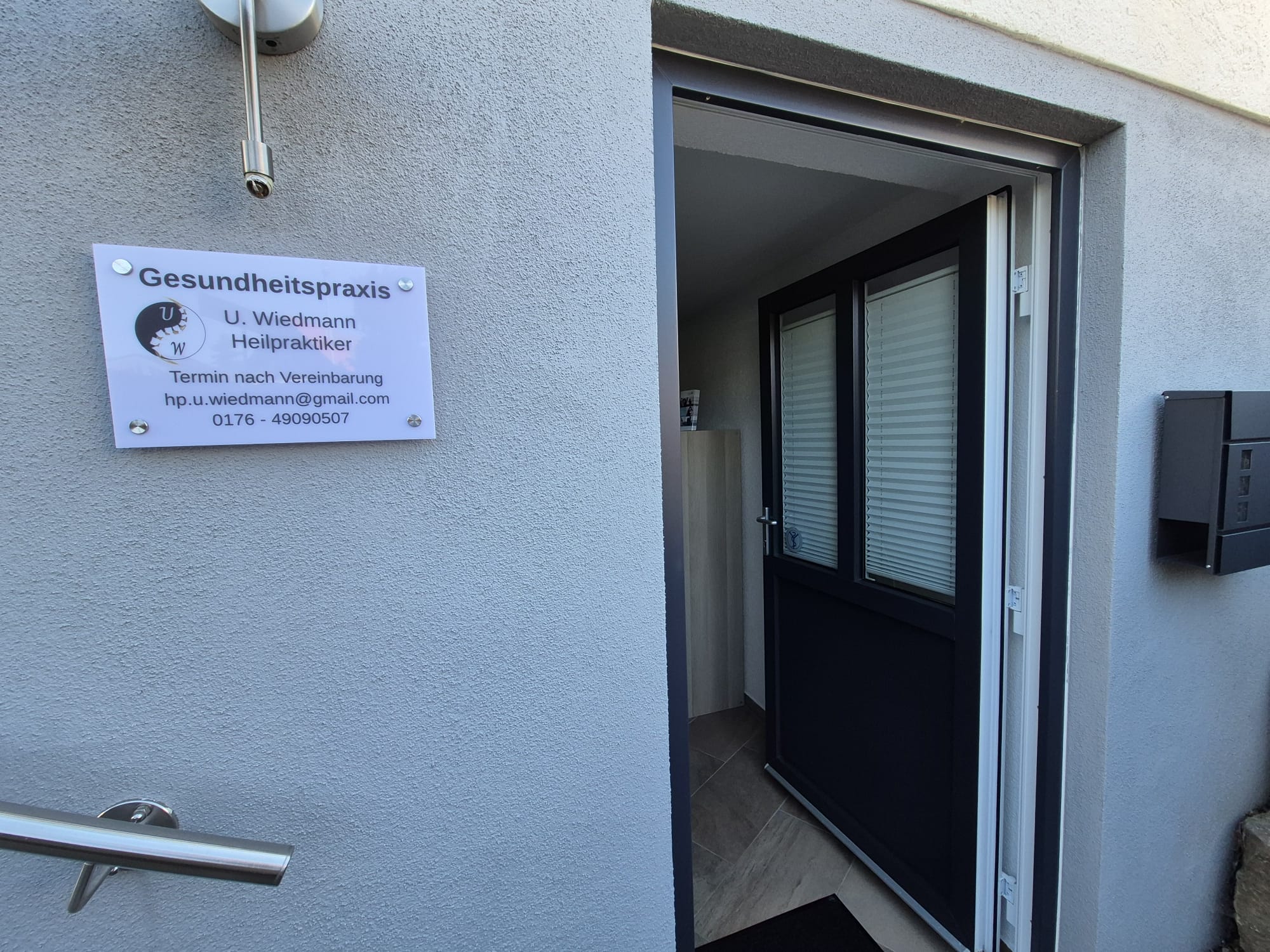 Eingang der Gesundheitspraxis Ulrike Wiedmann mit Praxisschild in Unteressendorf